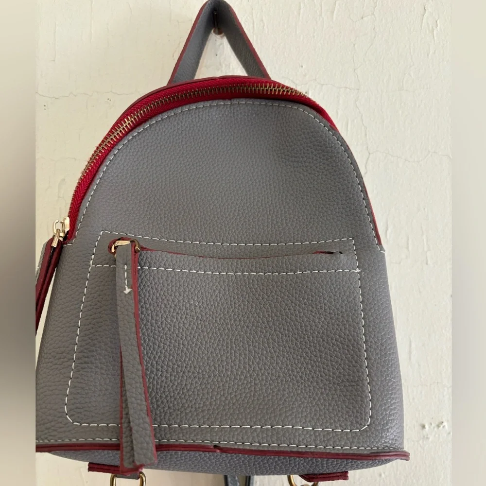 Small grey and maroon backpack with pocket in front and inside, cream interior